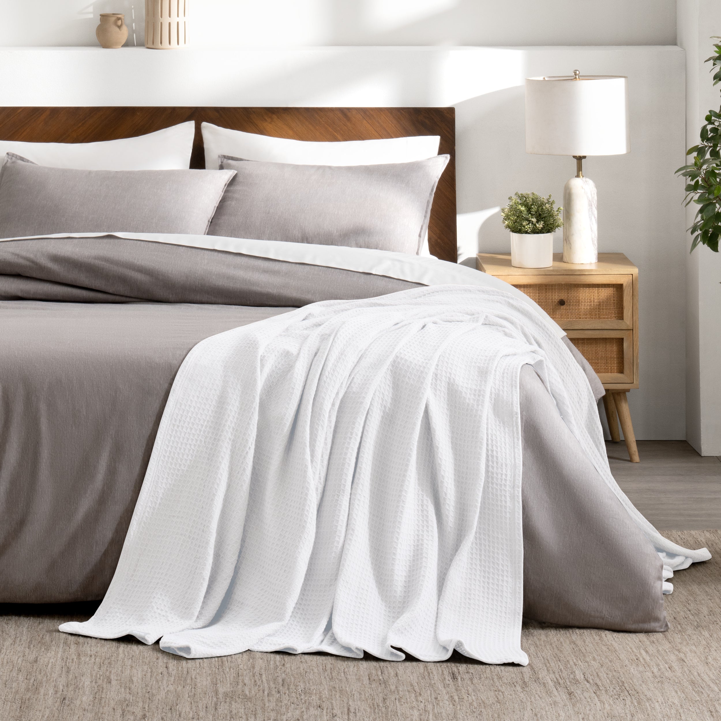 Bed with gray bedding and a throw blanket in a bedroom setting.
