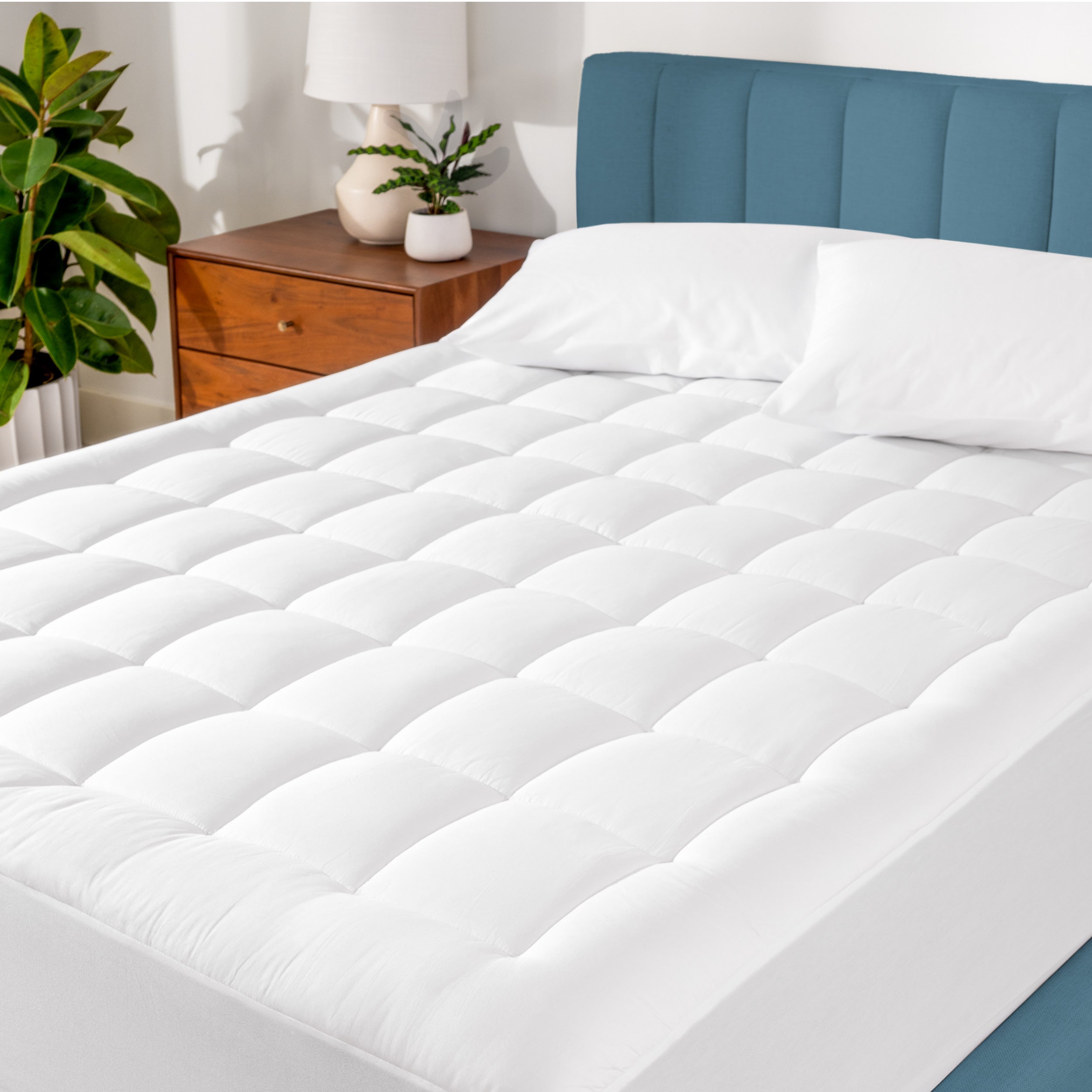 A cotton top mattress pad on a mattress in a modern bedroom.