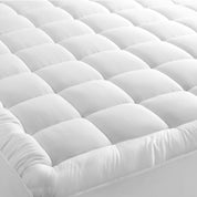 A mattress pad on a bed with 2 pillows on top