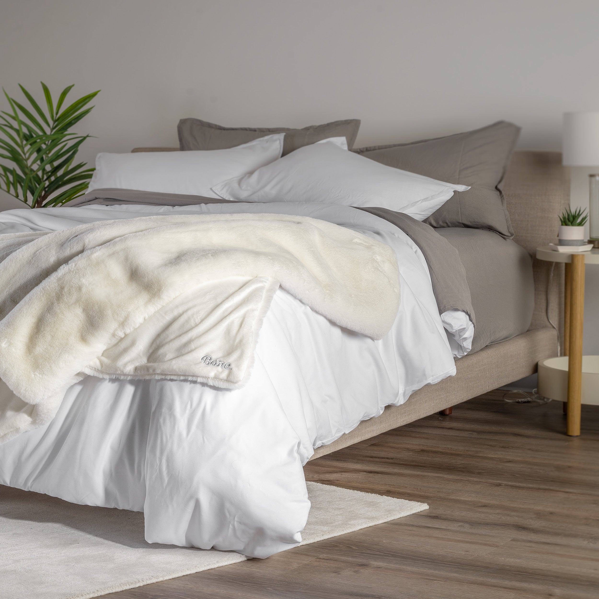 Blanket draped over a bed in a bedroom setting with a nightstand and lamp.