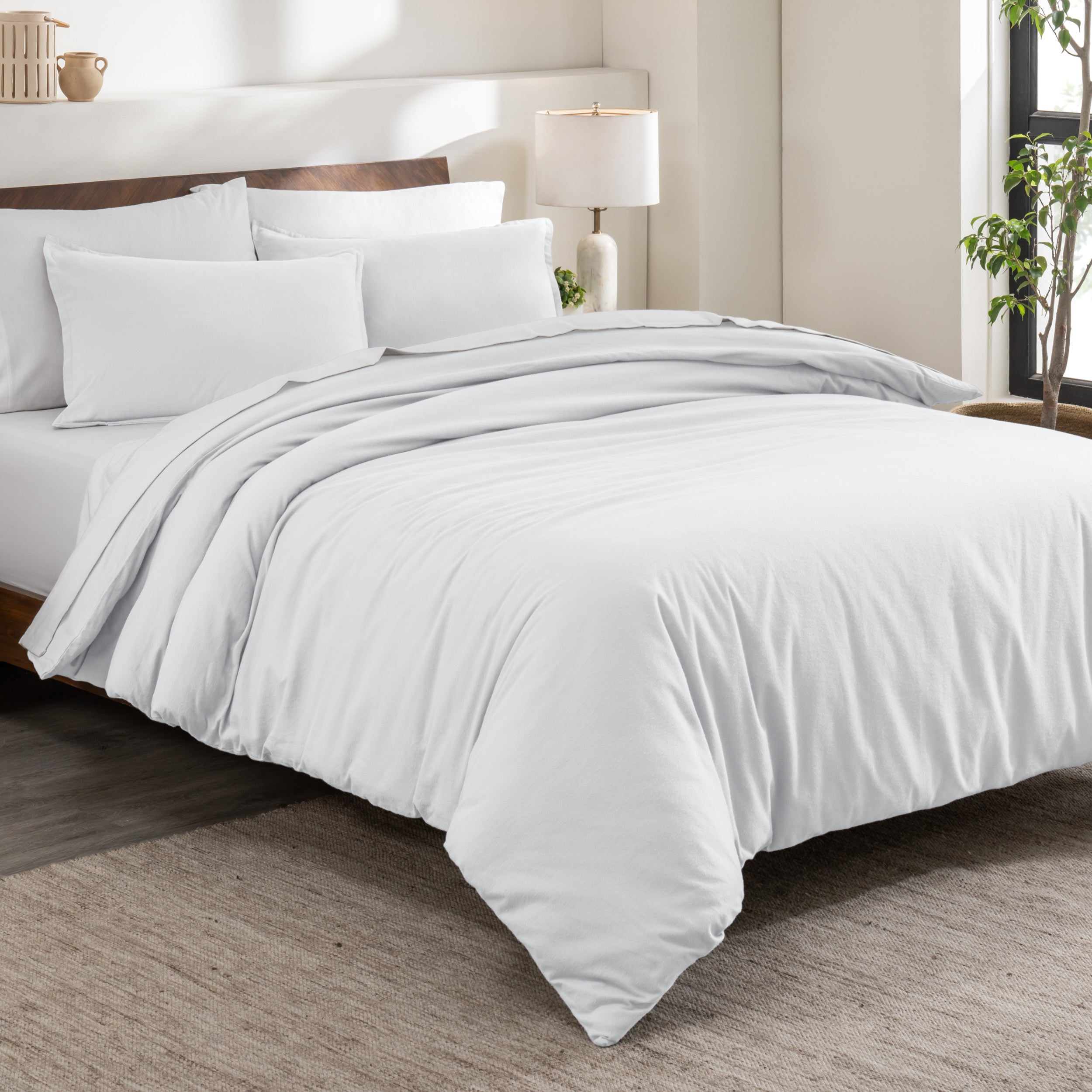Flannel duvet cover set on a bed in a bedroom with a lamp and plant in the background.