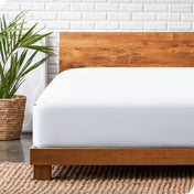 A modern bed with a wooden bed frame with a flannel fitted sheet on.