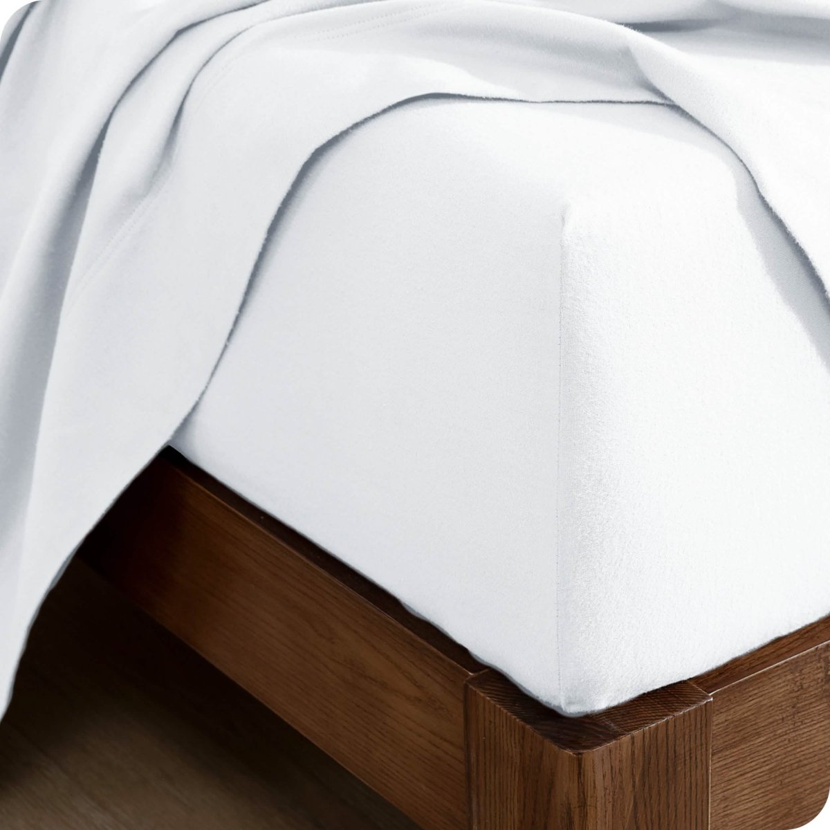 Corner of a bed with a flannel fitted sheet and top sheet on it