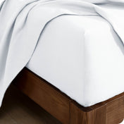 Corner of a bed with a flannel fitted sheet and top sheet on it