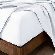 Close up of the corner of a mattress with a flannel fitted sheet and flat sheet on it