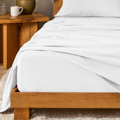 Bed with flannel bedding and wooden headboard and nightstand next to it.