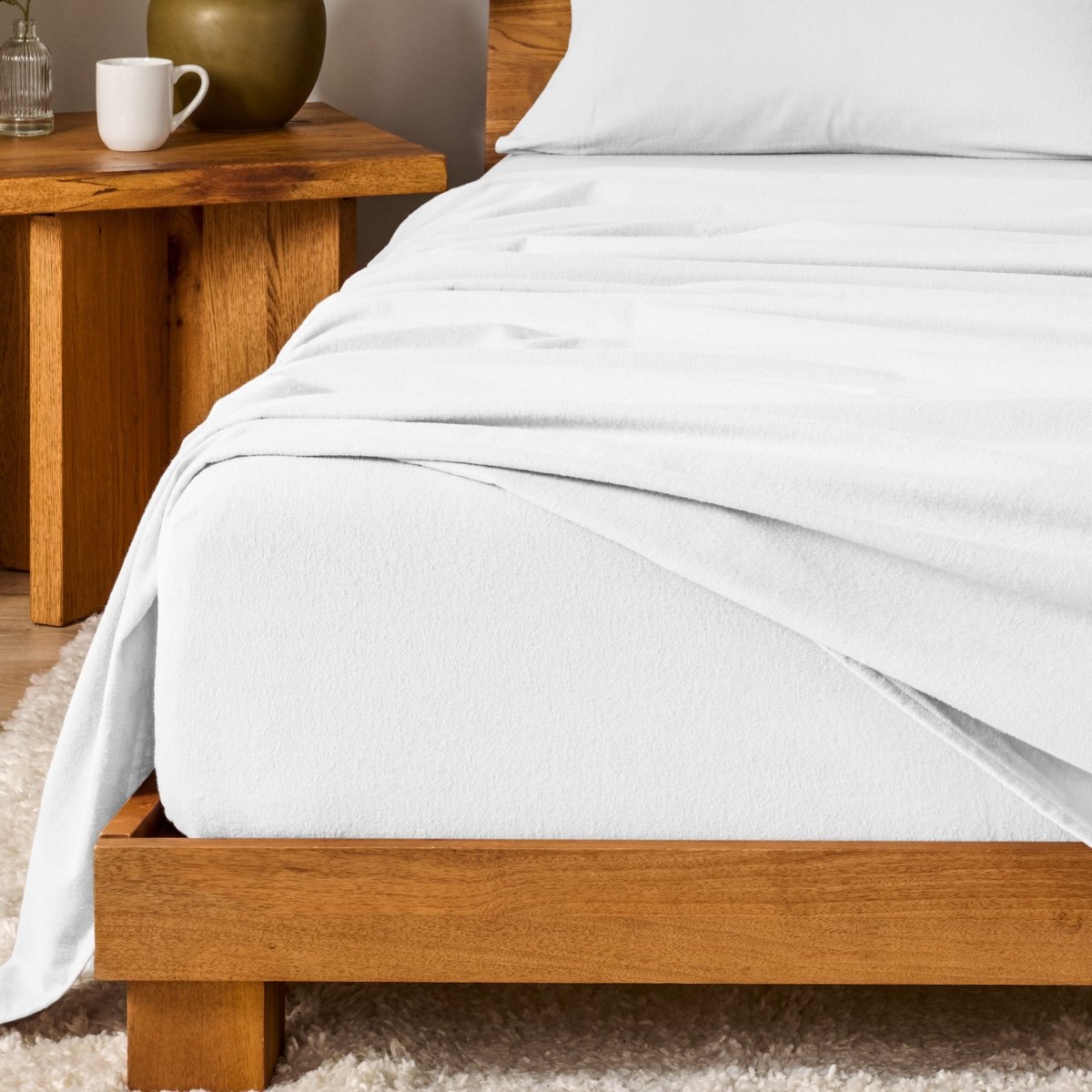 Bed with flannel bedding and wooden headboard and nightstand next to it.