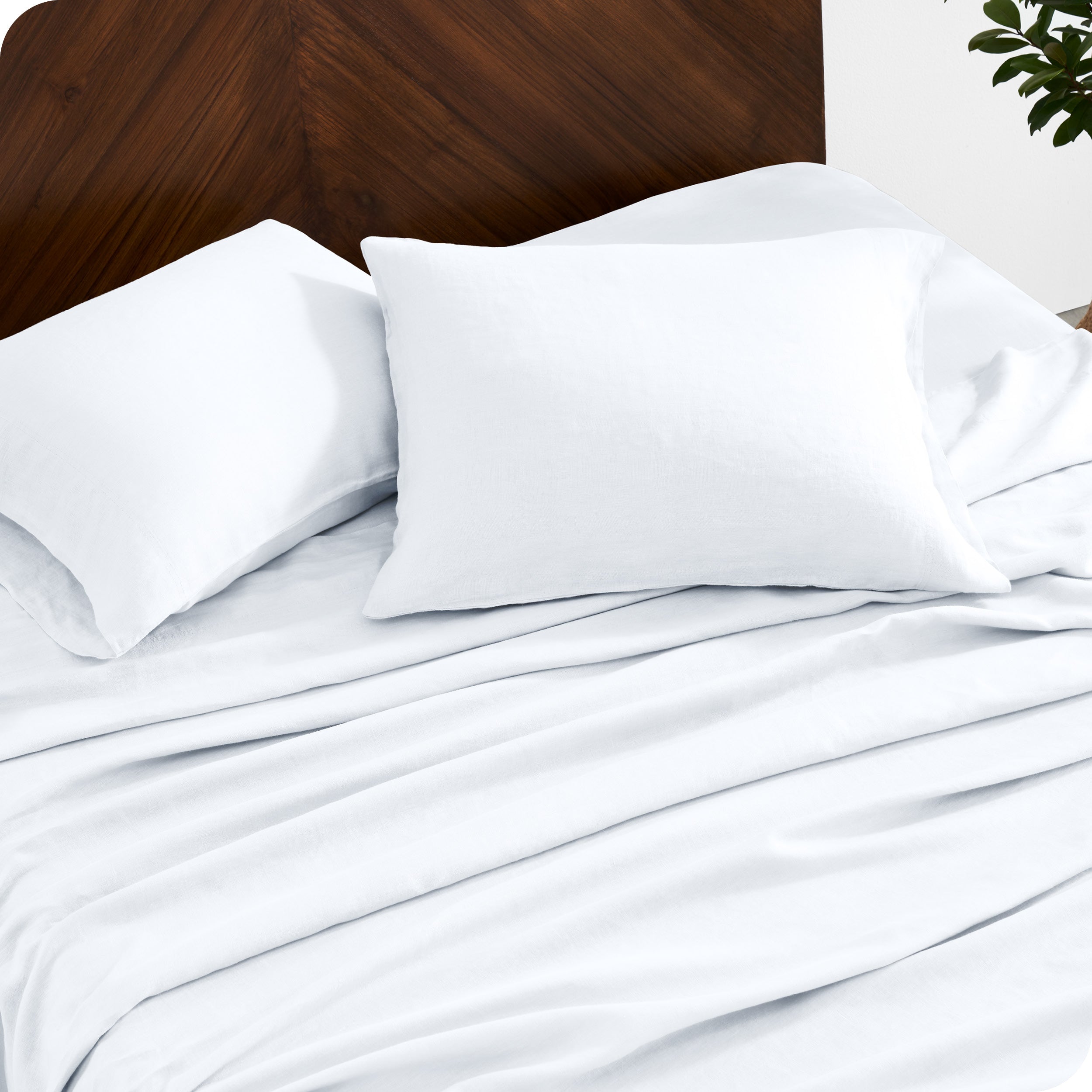 Close up of linen sheet set on a mattress with pillows inside the pillowcases