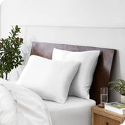 Two silk pillowcases over plush pillows, adorning a neatly made bed