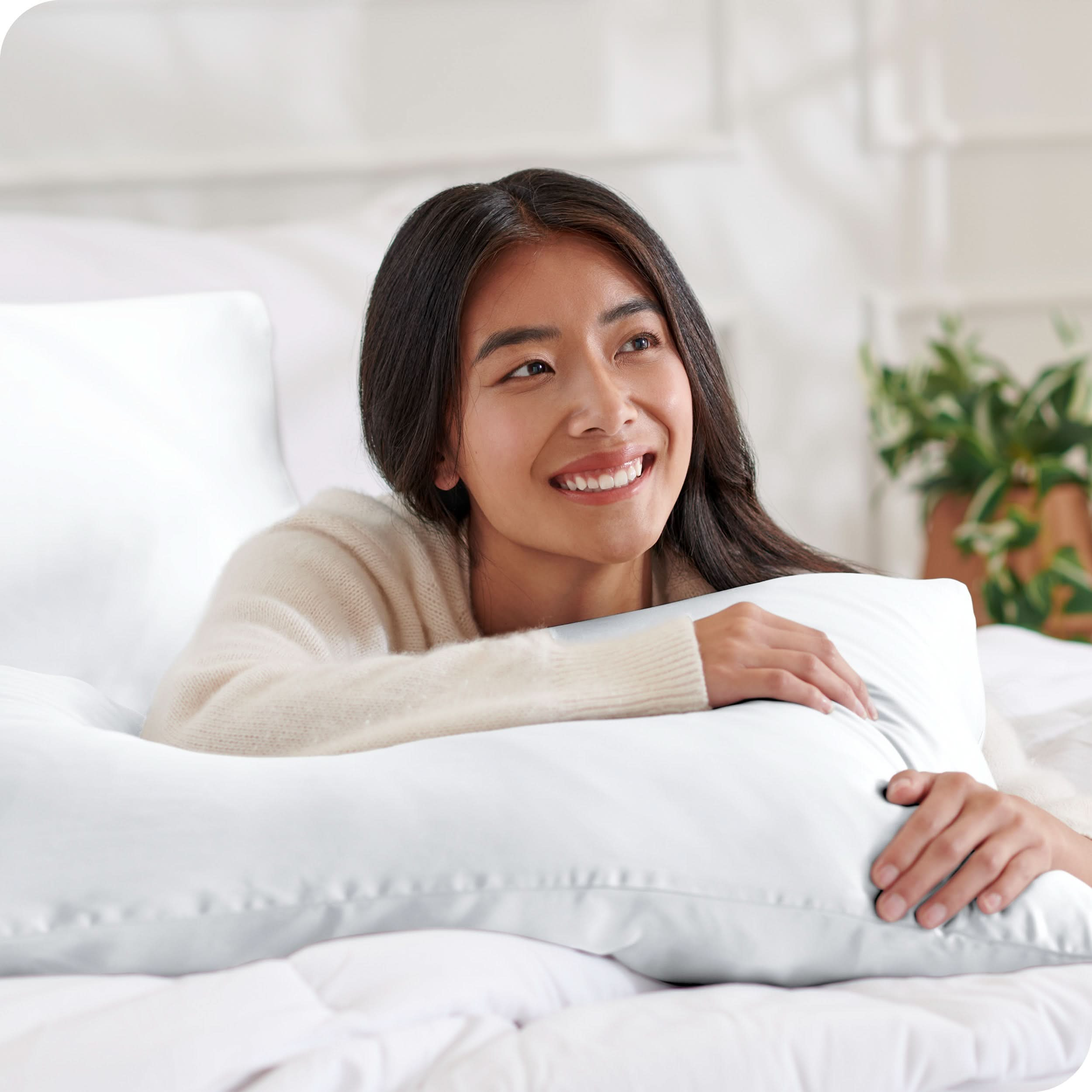 A woman on a bed with a silk pillowcase covered pillow