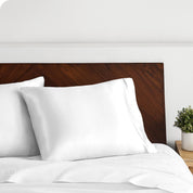 A white silk pillowcase on a pillow resting on a headboard