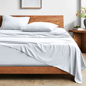 Bed with washed sheets and wooden headboard in a room setting.