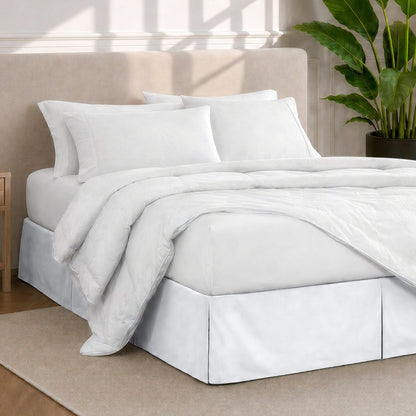 A modern bedroom with a bed skirt, comforter and sheets on the bed