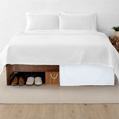 One side of a bed has shoes and a box under it while the other side has a bed skirt so that under the bed is hidden from view
