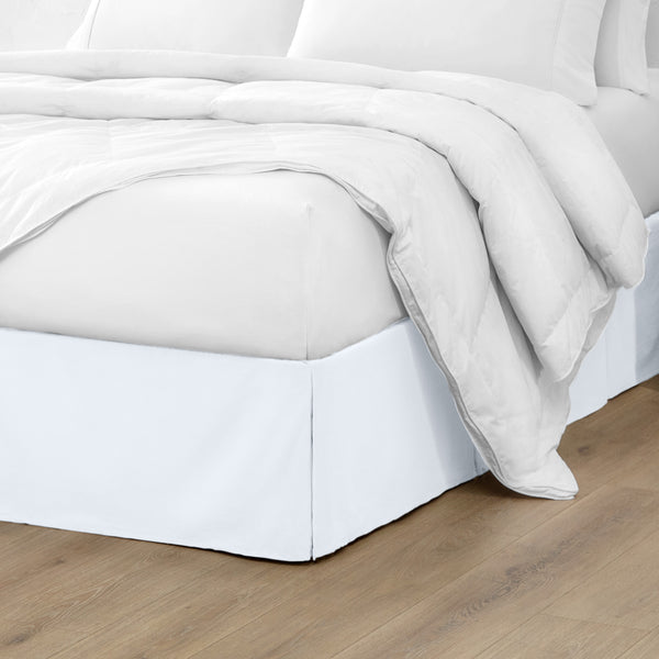 A modern bed with a microfiber bed skirt with pleats on the corners and midway on each side