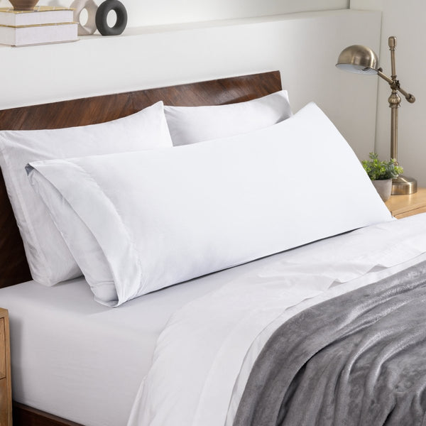 Bed sheets and pillows on a neatly made bed with a wooden headboard.