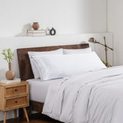 Bedroom with a wooden headboard and white bedding, featuring a nightstand and decorative items.