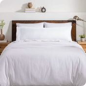 A body pillow cover on a pillow on a bed with other pillows and a duvet cover