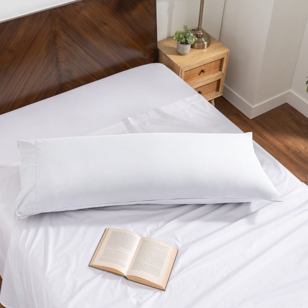 Pillowcase on a body pillow with a wooden headboard and plant in the background