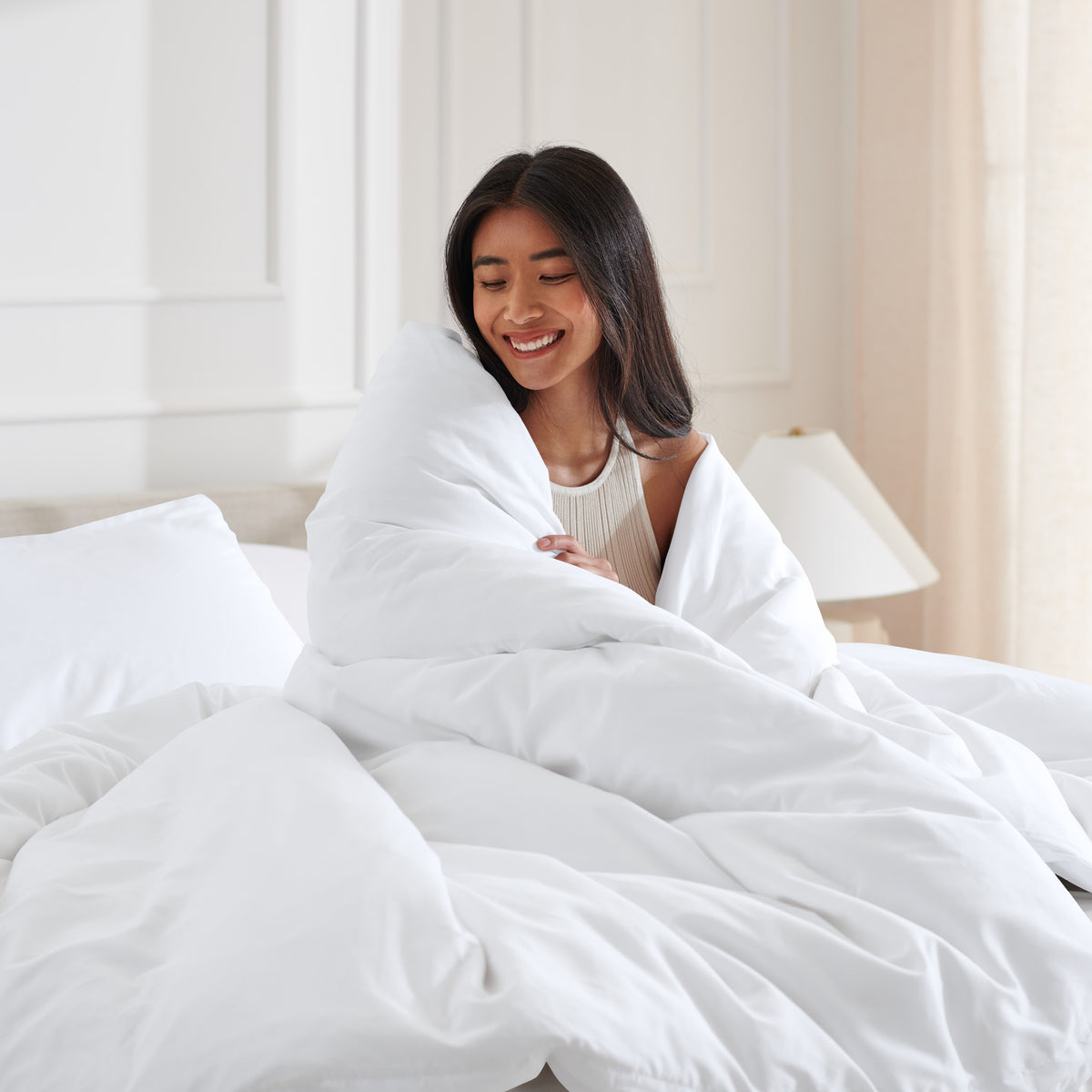 Woman smiling under duvet cover set in a bedroom setting