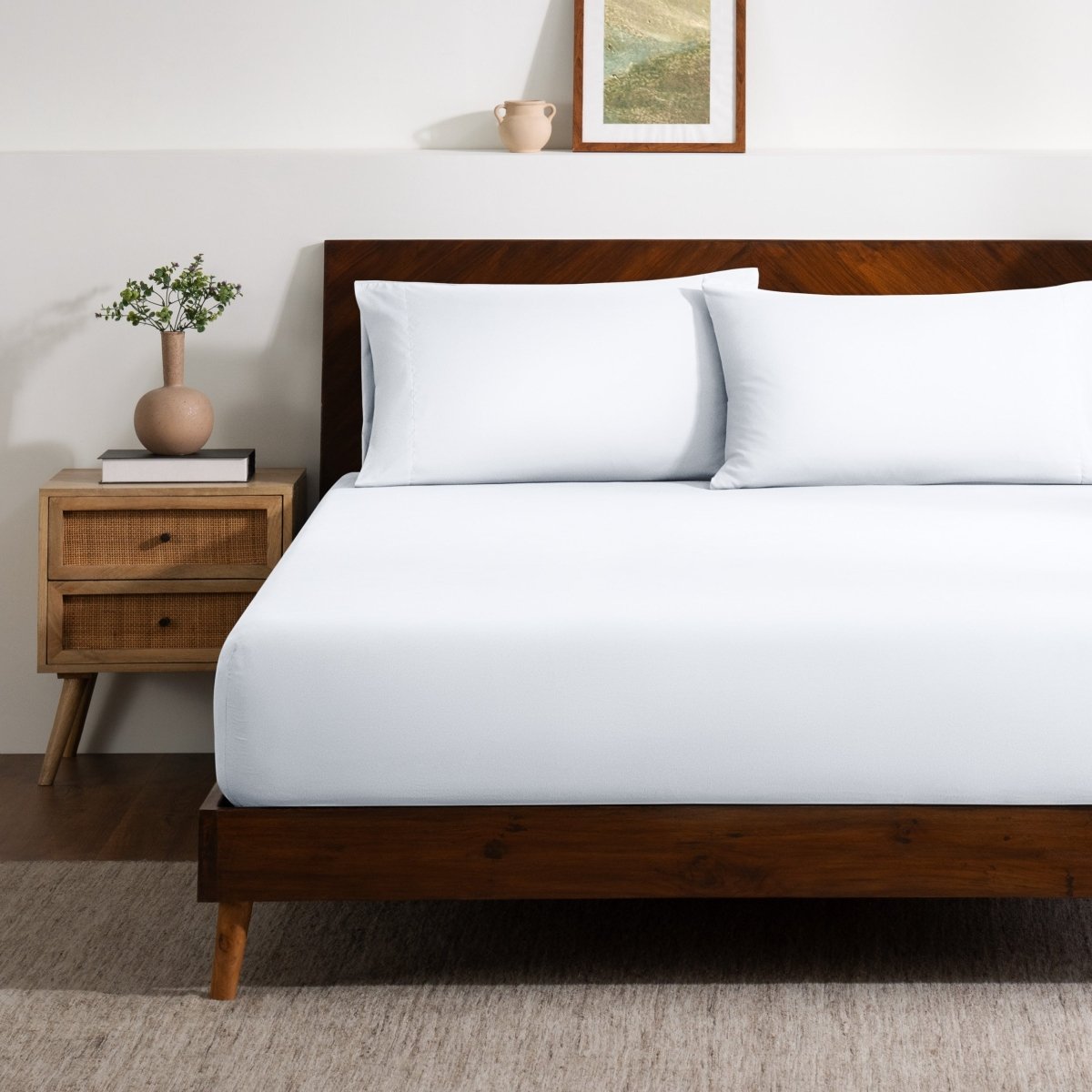 A bed made with a single fitted sheet and two matching pillowcases.