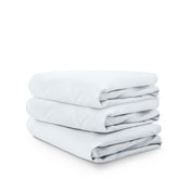 Stack of white folded crib sheets on a white background