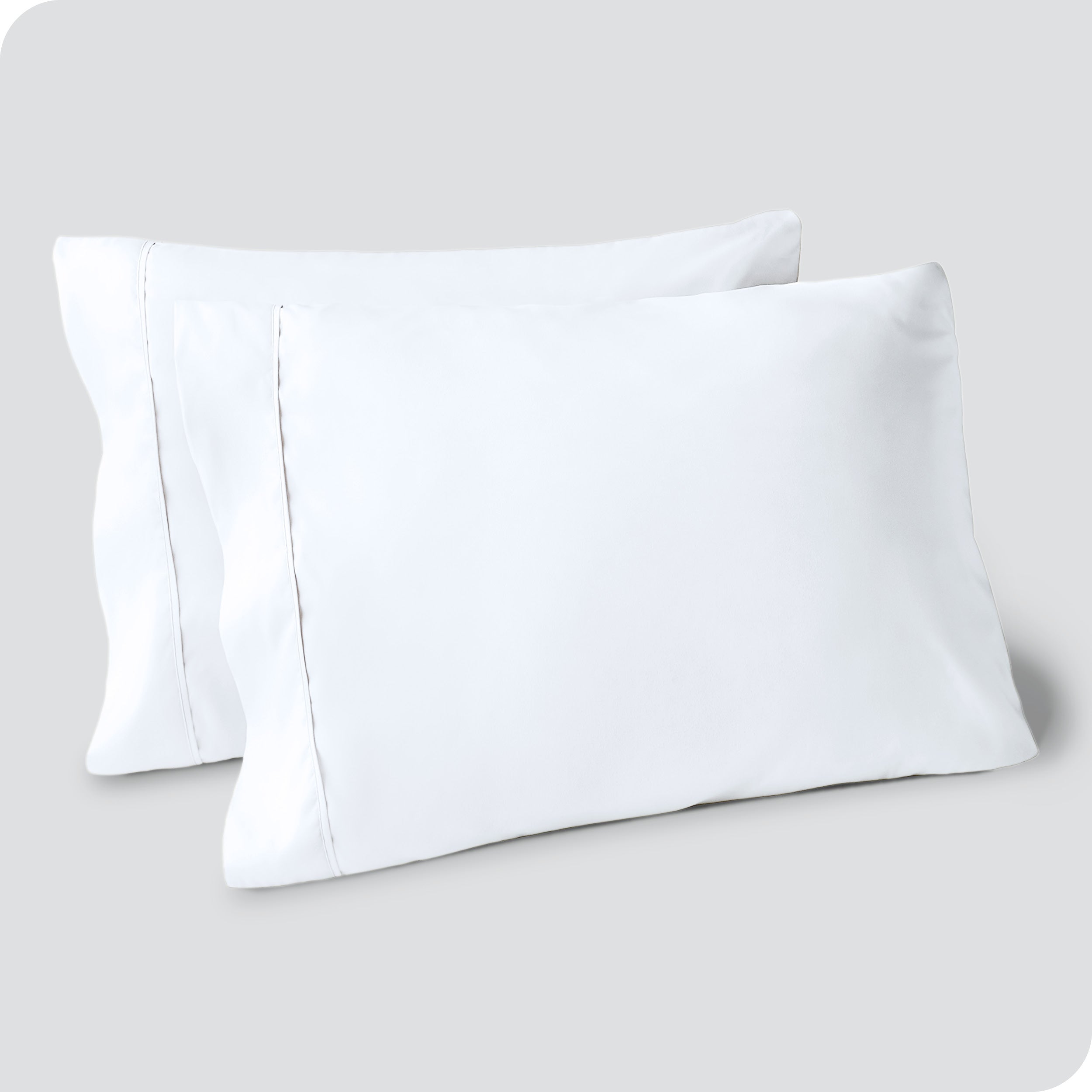 Two pillows on a white background with white pillowcases on them