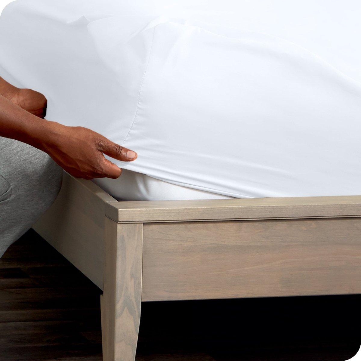 Person adjusting a fitted sheet on a mattress