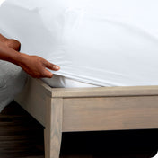 Person adjusting a fitted sheet on a mattress