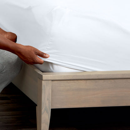 Person adjusting a fitted sheet on a mattress