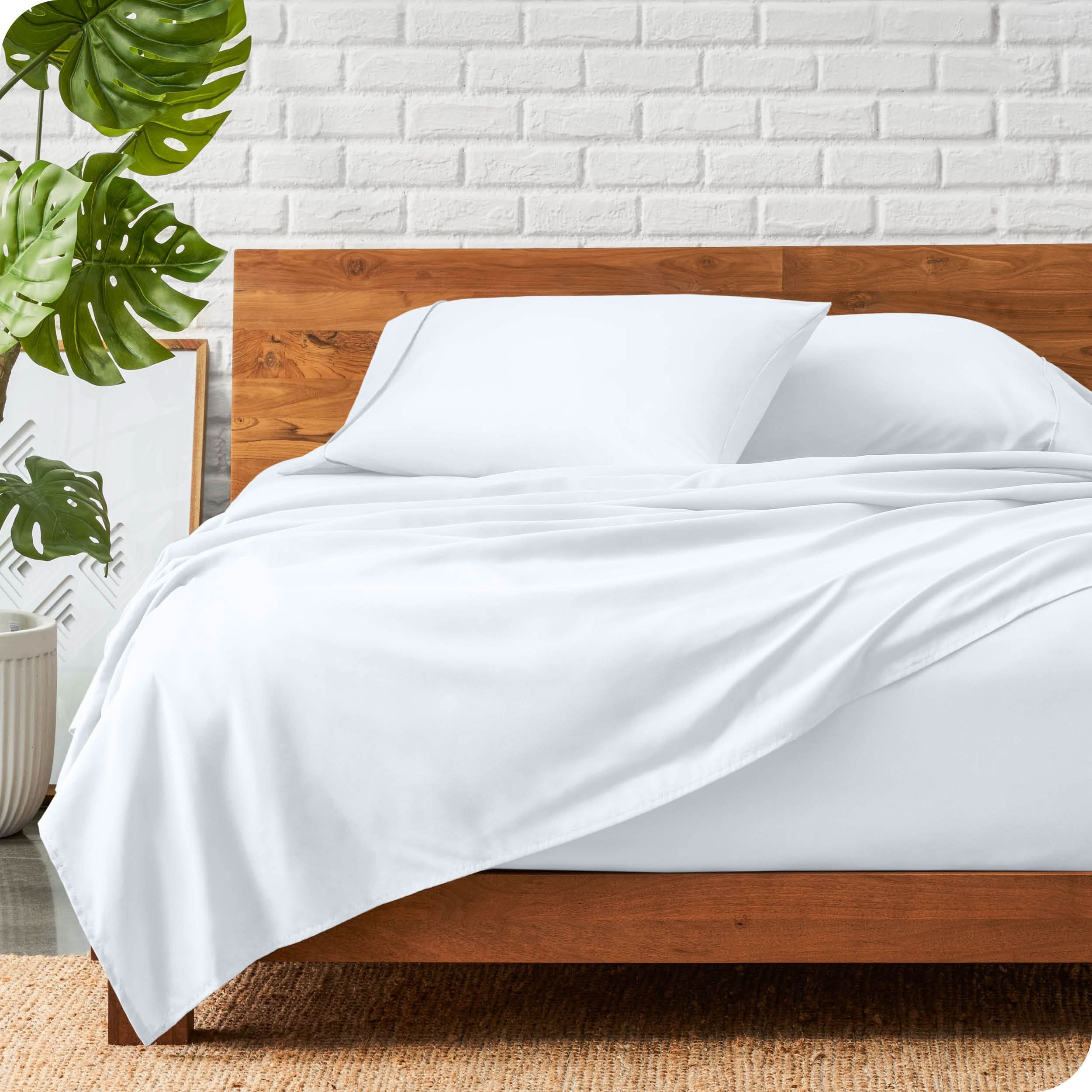 A wooden bed frame with a microfiber sheet set on the mattress.