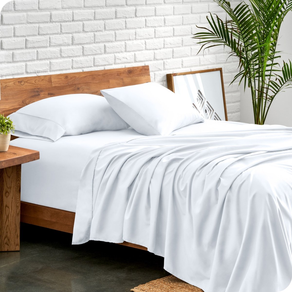 Bed with microfiber sheets against a white brick wall