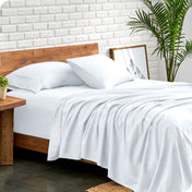Bed with microfiber sheets against a white brick wall