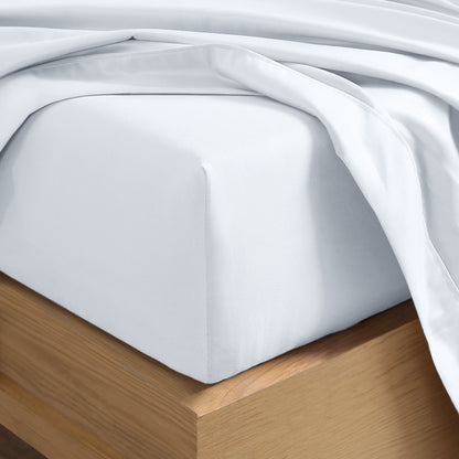 Close up of the corner of a mattress with a fitted sheet and flat sheet on it