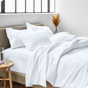 A side view of a bed made with microfiber sheets and a white duvet cover
