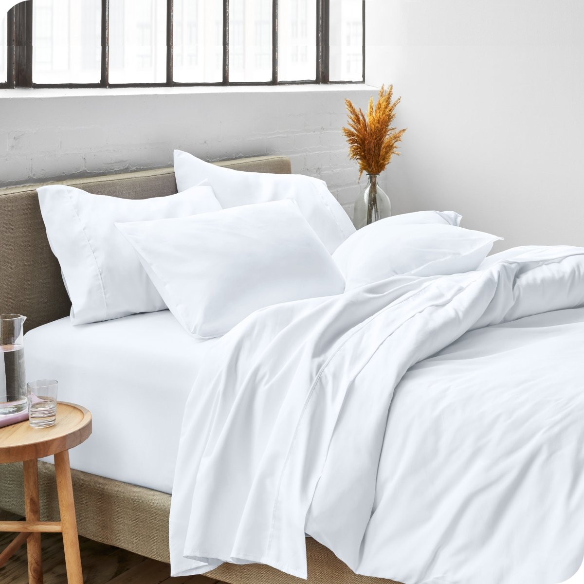 A side view of a bed made with microfiber sheets and a white duvet cover
