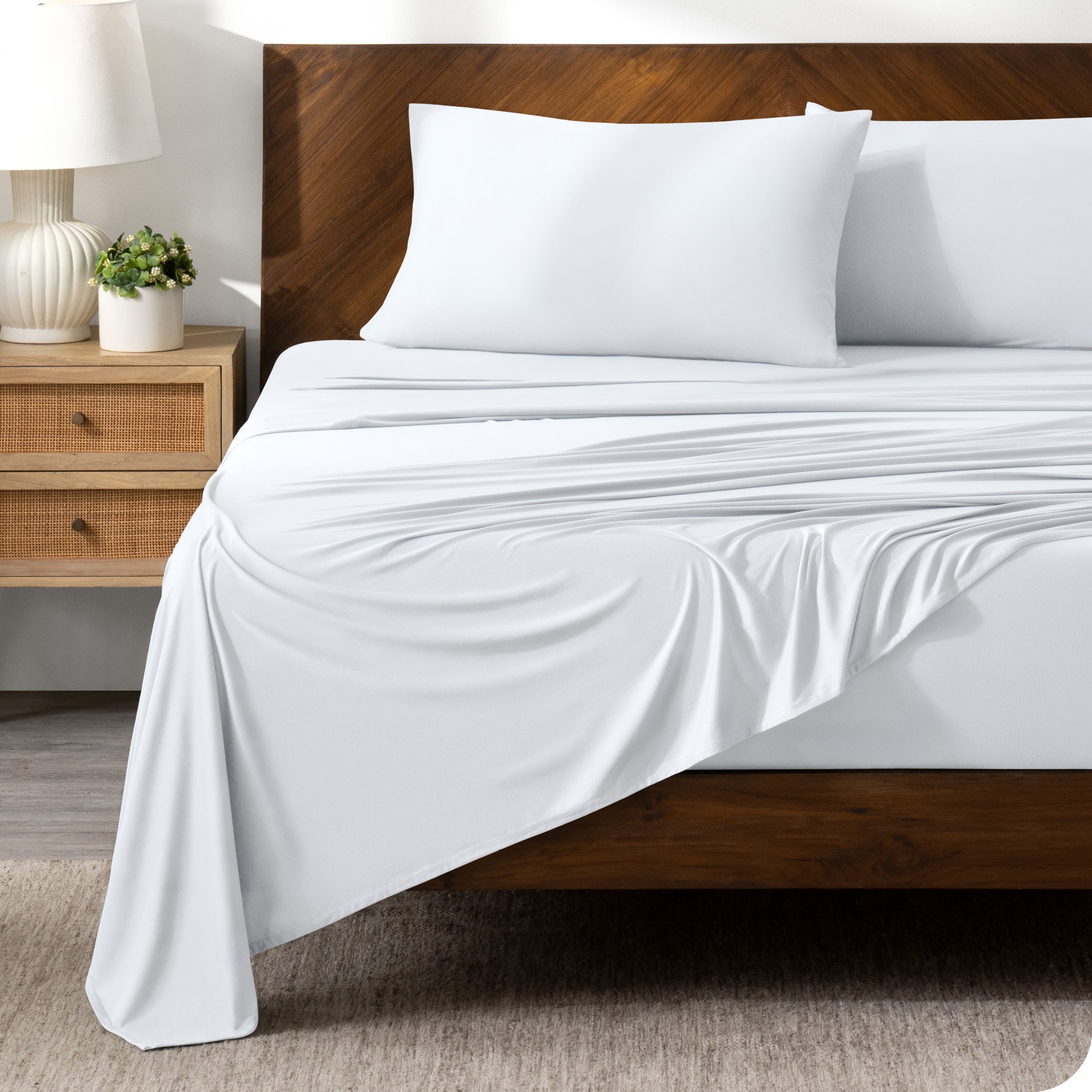 White sheet set on a bed with a dark wooden bed frame