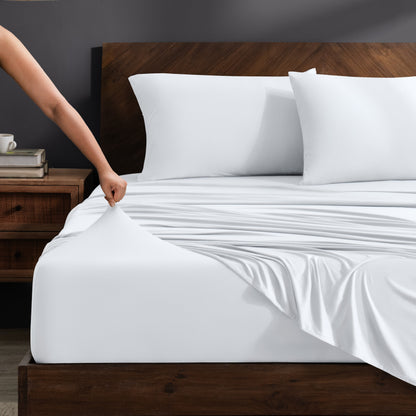 Person adjusting stretch sheets on a bed with a wooden headboard.