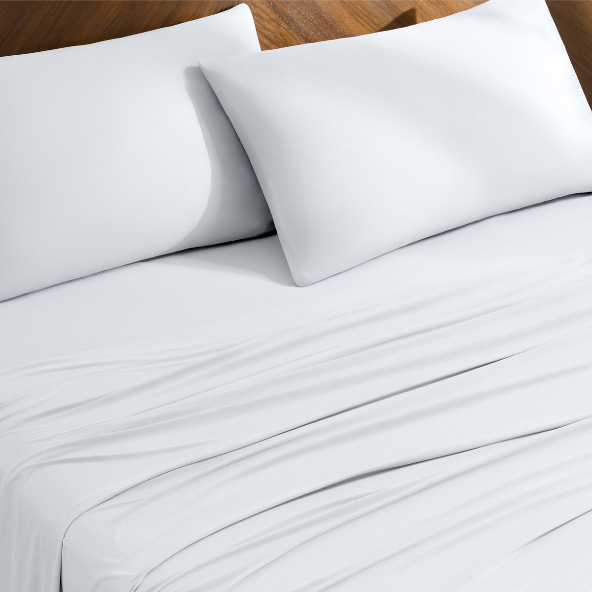 Bed sheets and pillowcases on a bed with a wooden headboard
