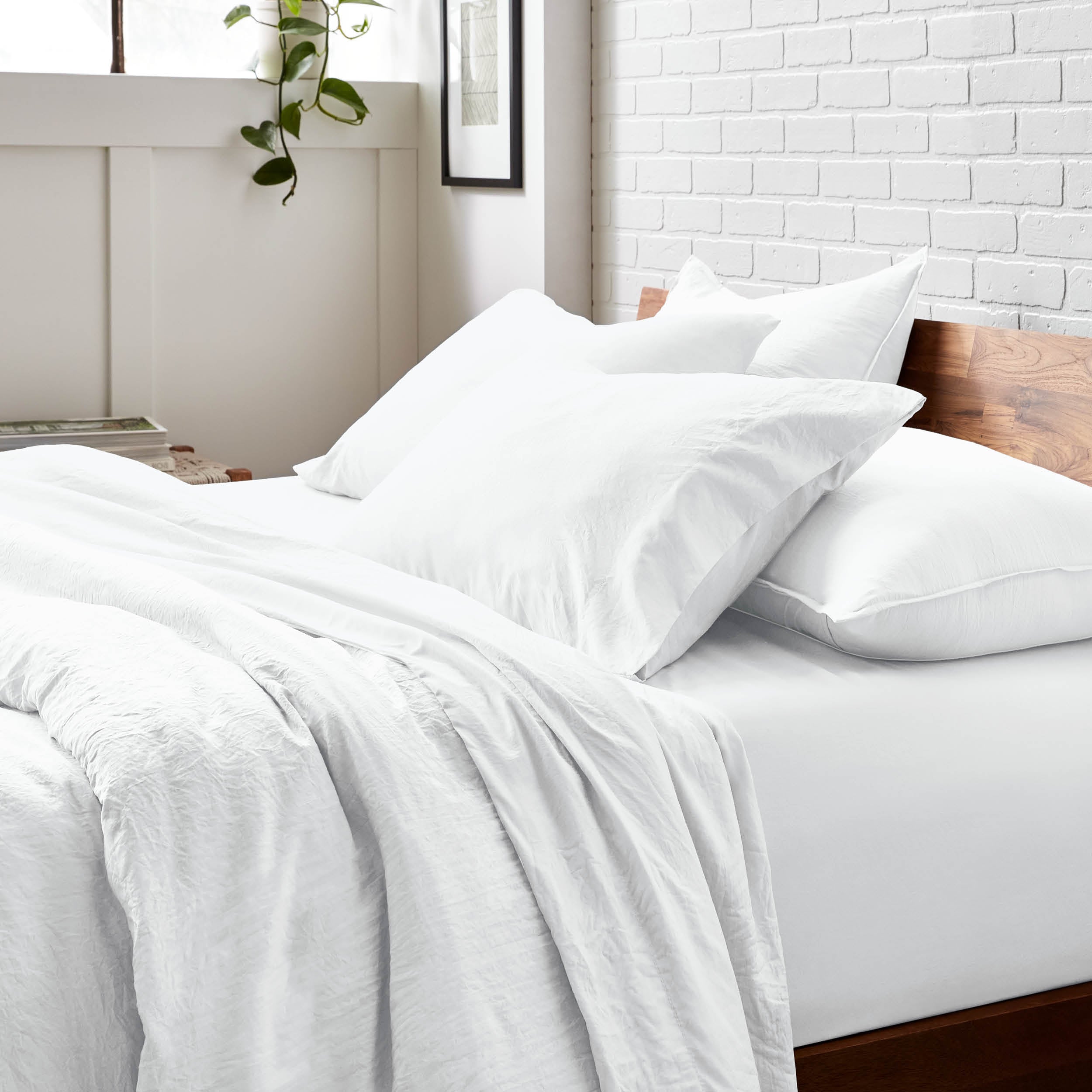 Bedding set on a bed with a white brick wall and window in the background