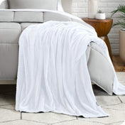 A microplush blanket is draped over the side and bottom of a neatly made bed.