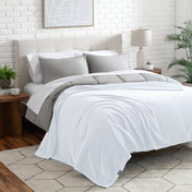 Neatly made bed with a blanket draped over the end of the bed