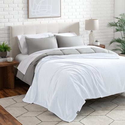 Neatly made bed with a blanket draped over the end of the bed
