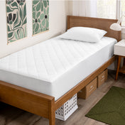 Wooden bed with white mattress cover in a room with decorative elements.