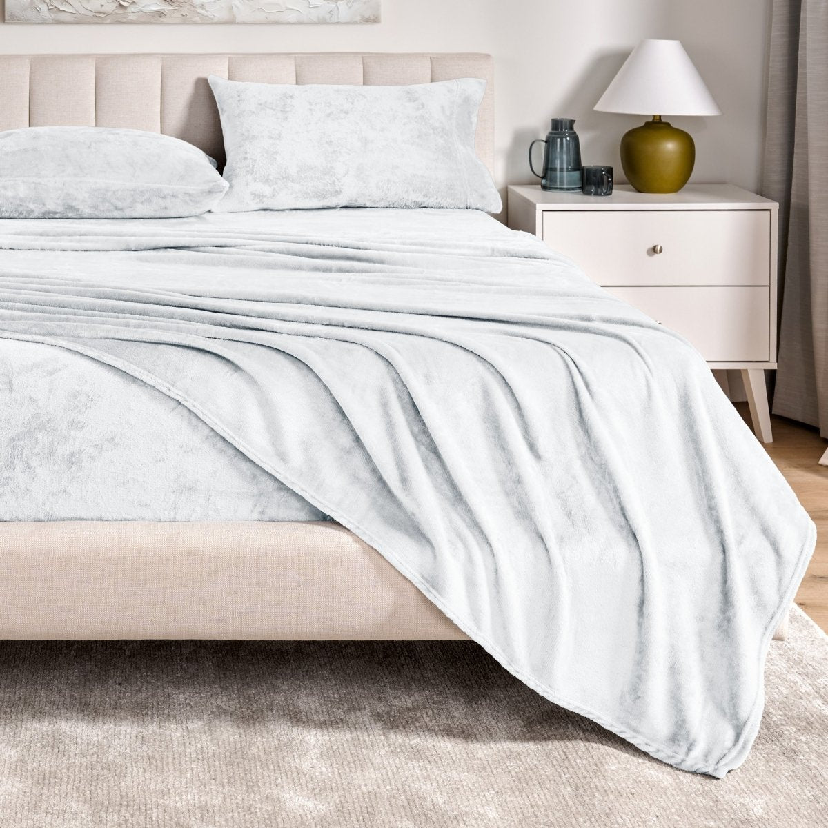 Microplush sheet set on a bed in a bedroom setting with a nightstand and lamp.
