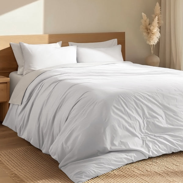 Bed with percale duvet cover set and wooden headboard in a room with a vase and decorative items.