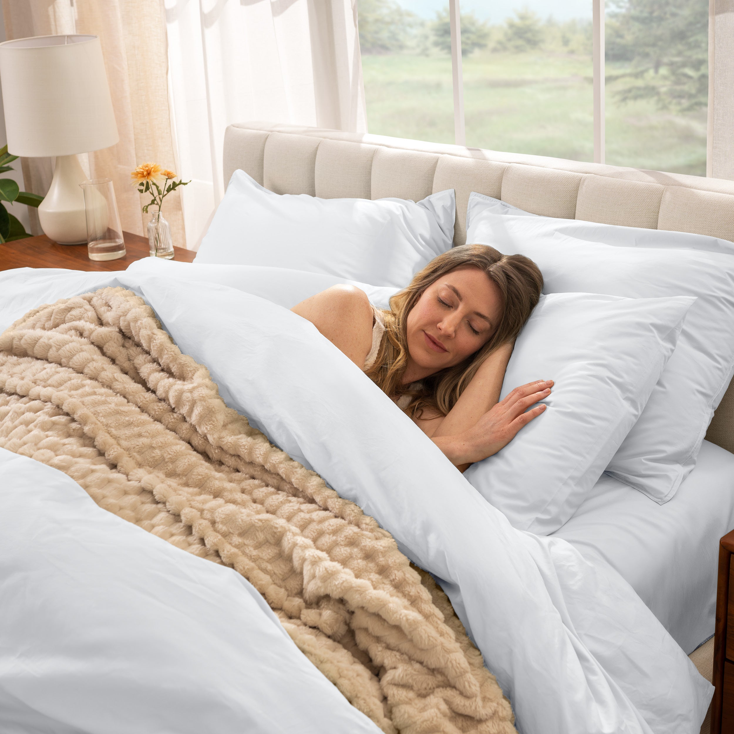 Woman sleeping in a bed with percale bedding and beige blanket