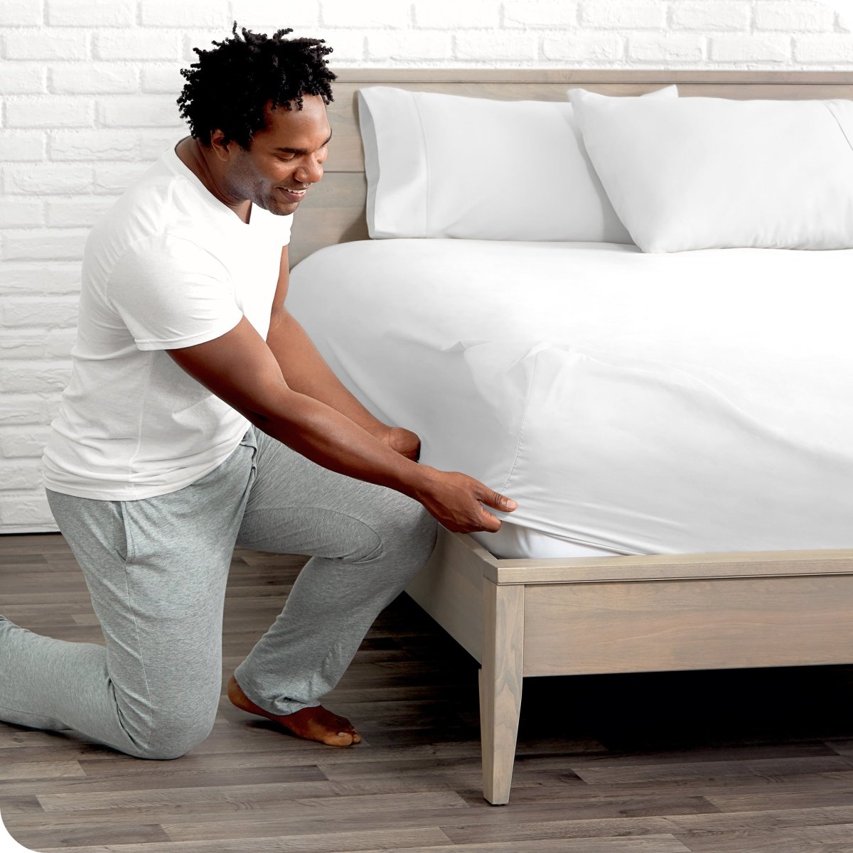 Man putting the corner of fitted sheet on a mattress