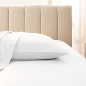 Sateen pillowcase on a bed with a beige headboard