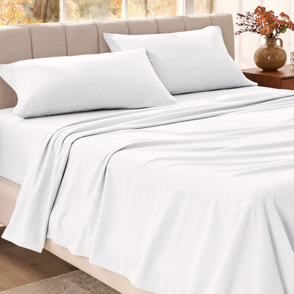 Bed sheets on a neatly made bed in a bright bedroom with large windows.